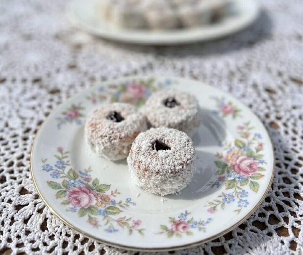 Tri Spojena čajna kolutića uvaljana u kokos i punjena džemom od šljiva na cvjetnom tanjiru